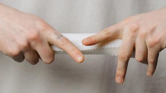 White textured adult toy held between two hands, showcasing grip and design details
