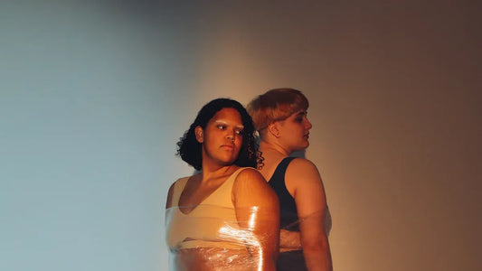Two women in intimate poses, wrapped in clear film, evoking sensual adult themes.