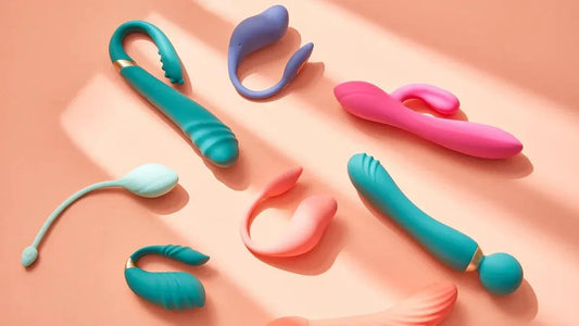 Assorted colorful vibrators and adult toys on soft pink background, featuring premium designs for intimate pleasure.