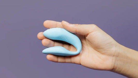Hand holding a light blue curved adult toy for intimate pleasure