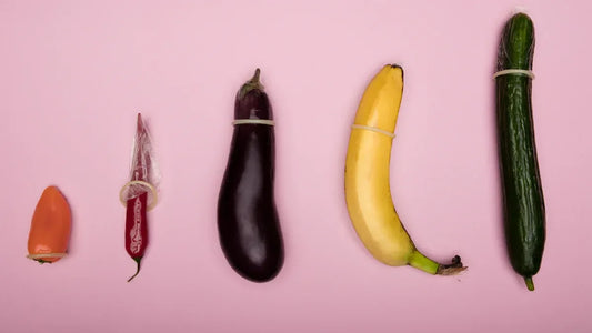Fruits and veggies with condoms: pepper, chili, eggplant, banana, cucumber on pink background